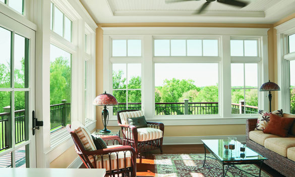 Open room with two chairs, a lamp, and large windows looking at trees